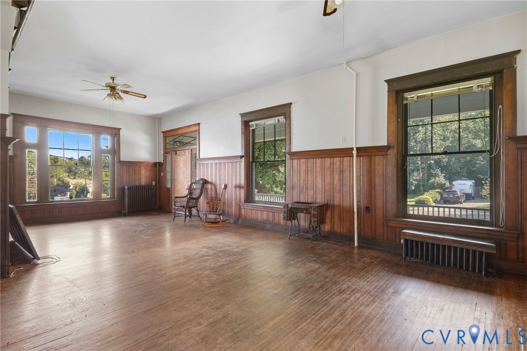Hardwood flooring, wood paneling, decorative window trim, a large picture window, and a ceiling fan Hardwood flooring, wood paneling, decorative window trim, a large picture window, and a ceiling fan