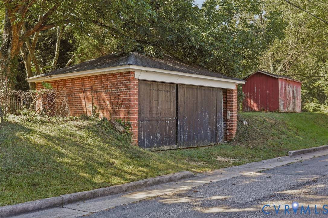 Brick outbuilding with a low-slope roof and wooden double doors