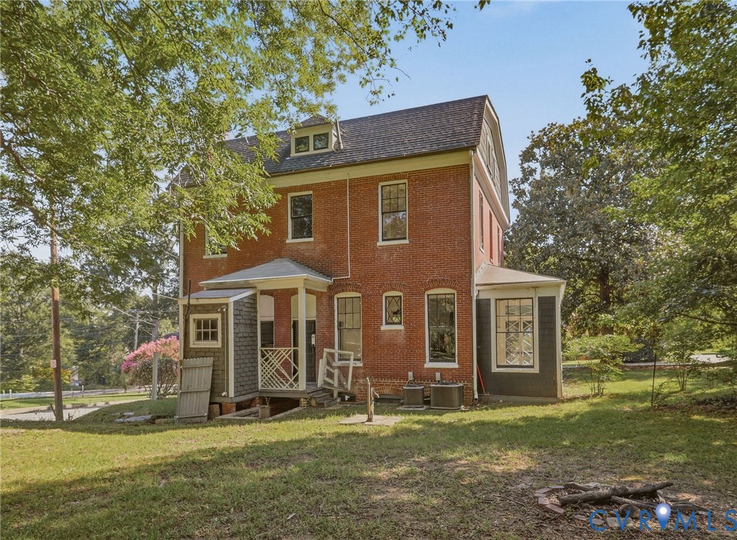 Brick exterior with multiple dormer windows, covered entry porch, and a side-mounted HVAC unit