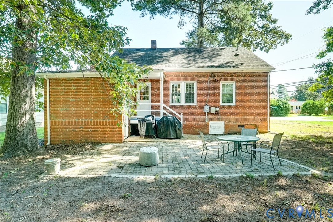 Brick exterior construction with white window trim and a paved patio