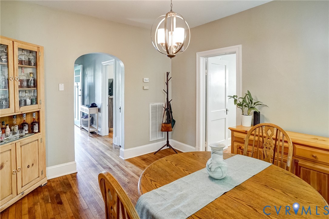 Hardwood flooring, arched doorway, and a modern orb-style pendant light fixture