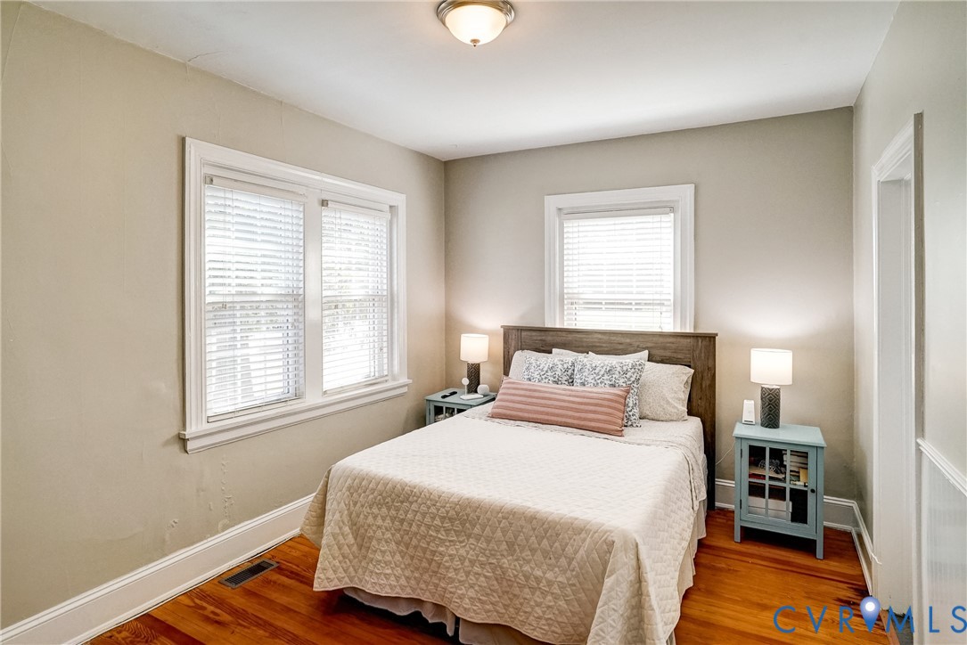 Wood flooring, multiple windows with blinds, recessed lighting fixture, and a paneled door