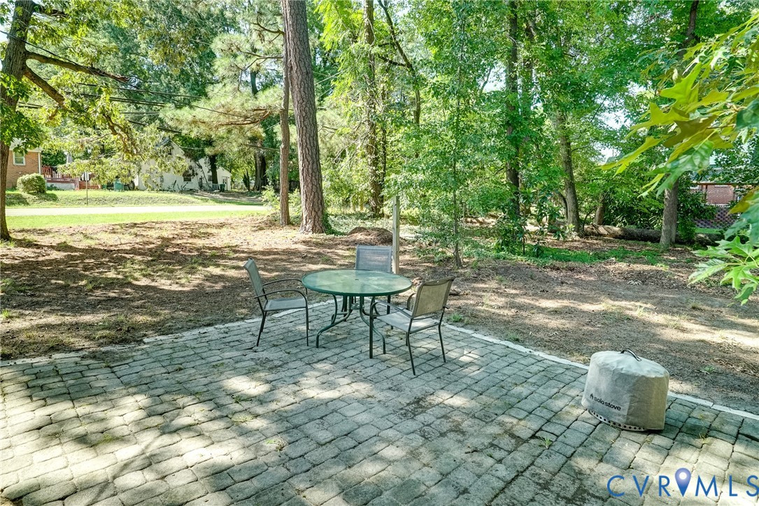 Paver patio with a tree-lined perimeter and mature trees