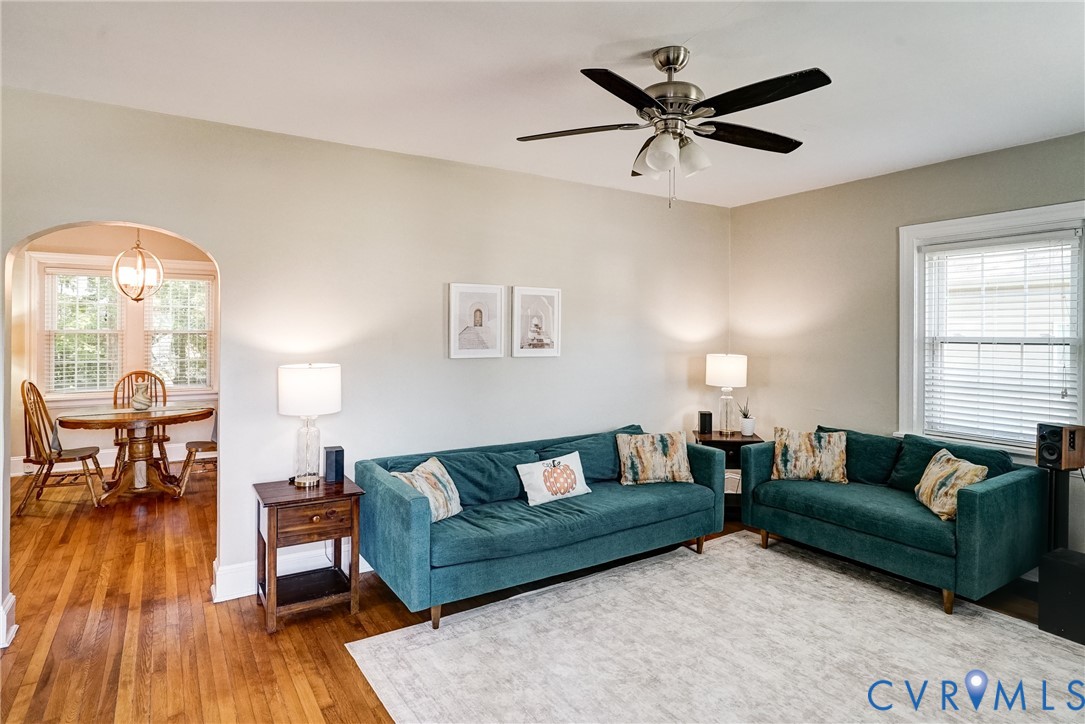 Wood-finish flooring throughout, arched doorway, and ceiling fan with integrated lighting