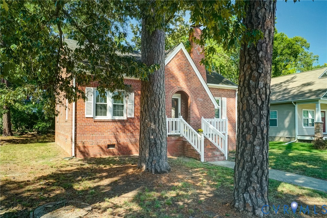 Brick exterior featuring a gabled roofline, decorative white shutters, and an arched entry