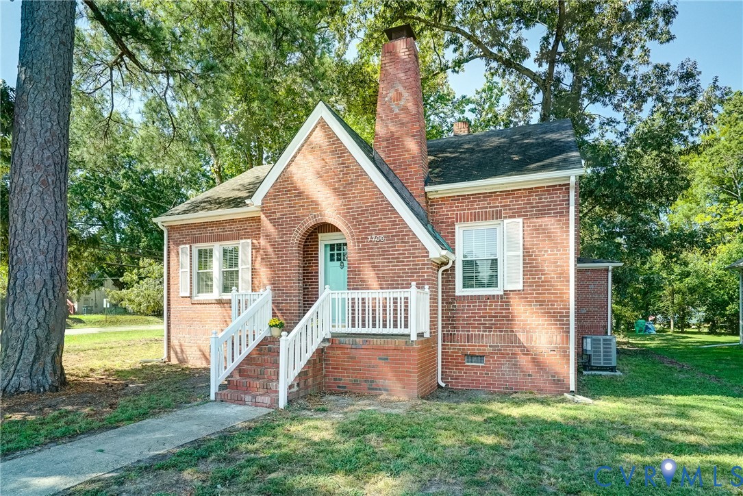 Brick exterior with a prominent chimney, arched entryway, white railings, and white window shutters