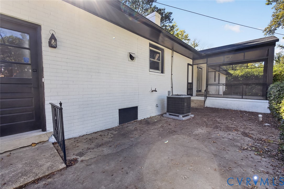 Painted brick exterior featuring a screened-in porch with metal framing, concrete patio, and exterior wall-mounted lantern-style lighting