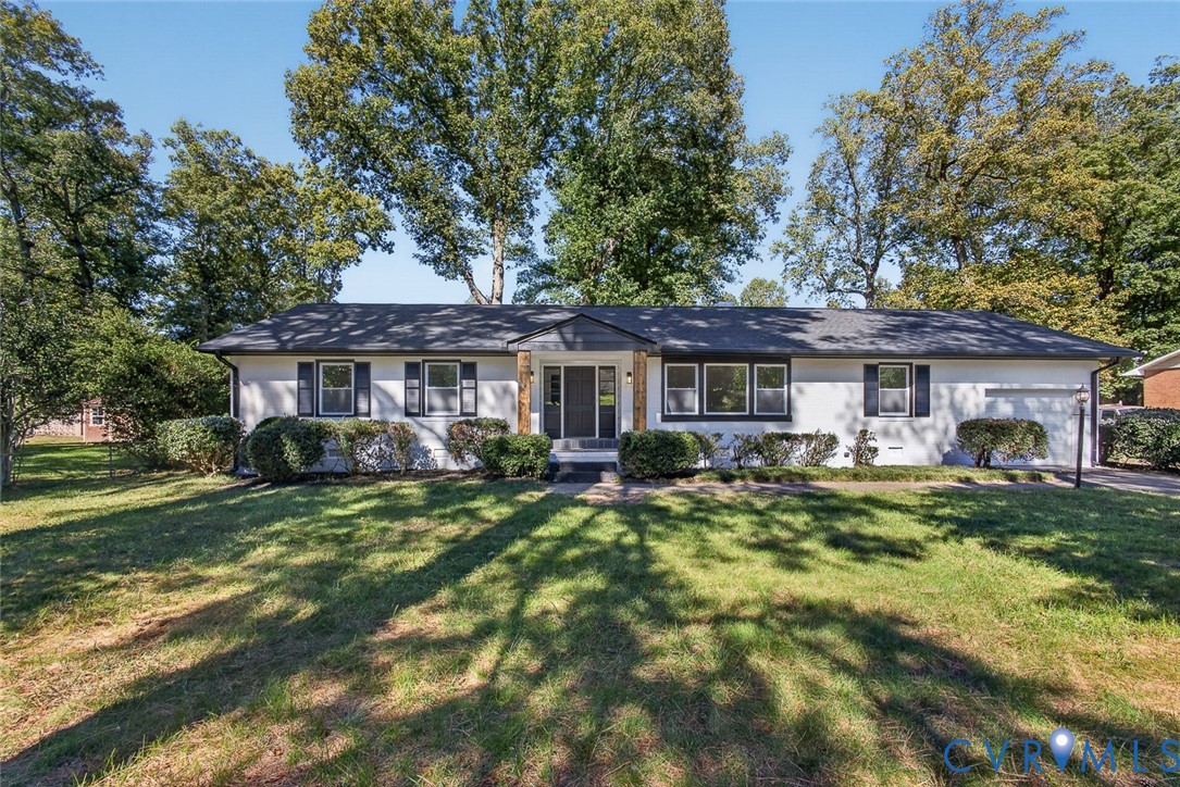 Single-story residence featuring a painted brick exterior, dark-trimmed window shutters, an asphalt shingle roof, and an integrated garage Single-story residence featuring a painted brick exterior, dark-trimmed window shutters, an asphalt shingle roof, and an integrated garage