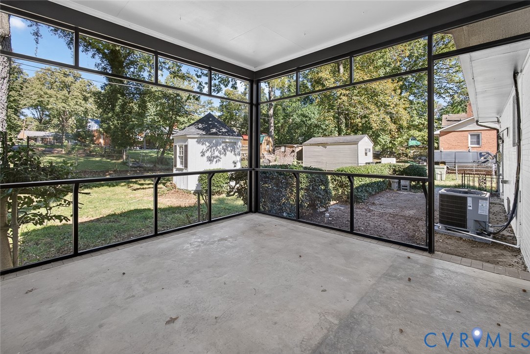 Screened-in porch featuring full-height glass panels, black metal framing, and concrete flooring