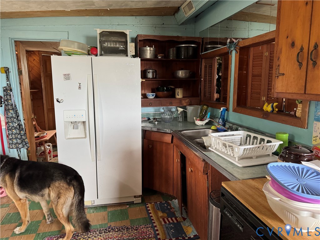 Kitchen area featuring wood cabinetry, open shelving, laminate countertops, and a double-basin sink