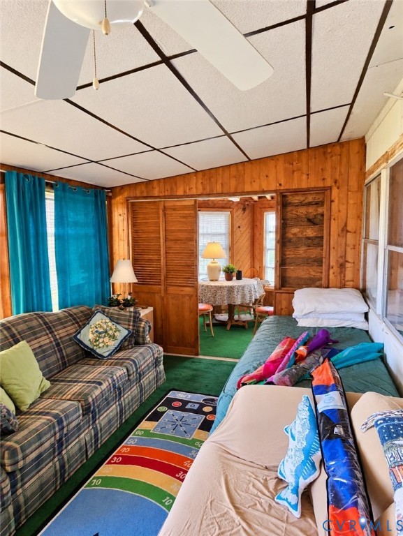Wood-paneled room featuring a ceiling fan, wall sconce, and louvered bifold doors