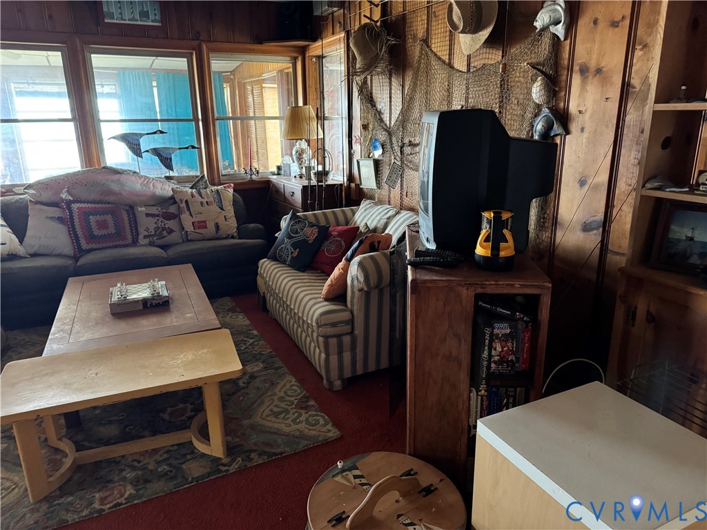 Living space featuring wood-paneled walls, large windows, and built-in shelving