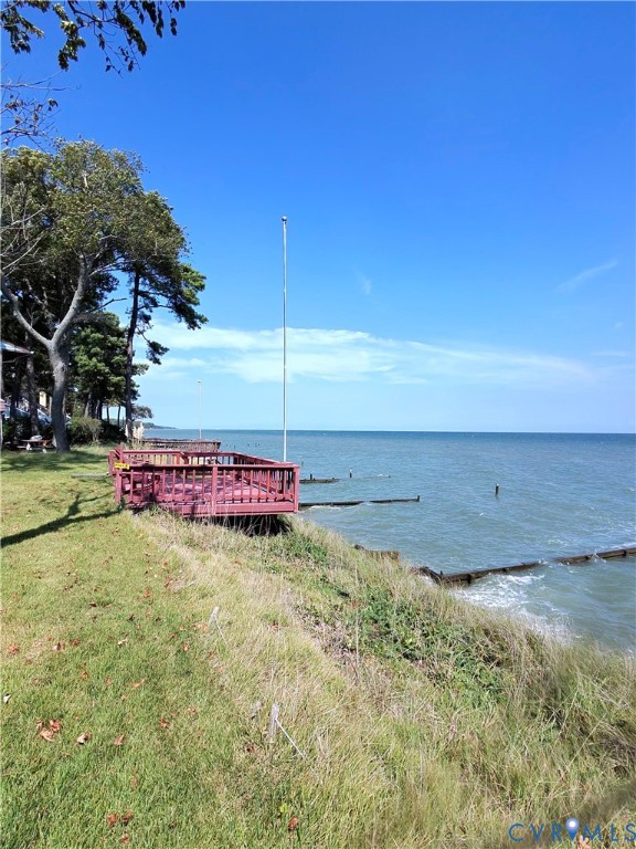 Waterfront property with a red-stained wood deck, overlooking expansive water