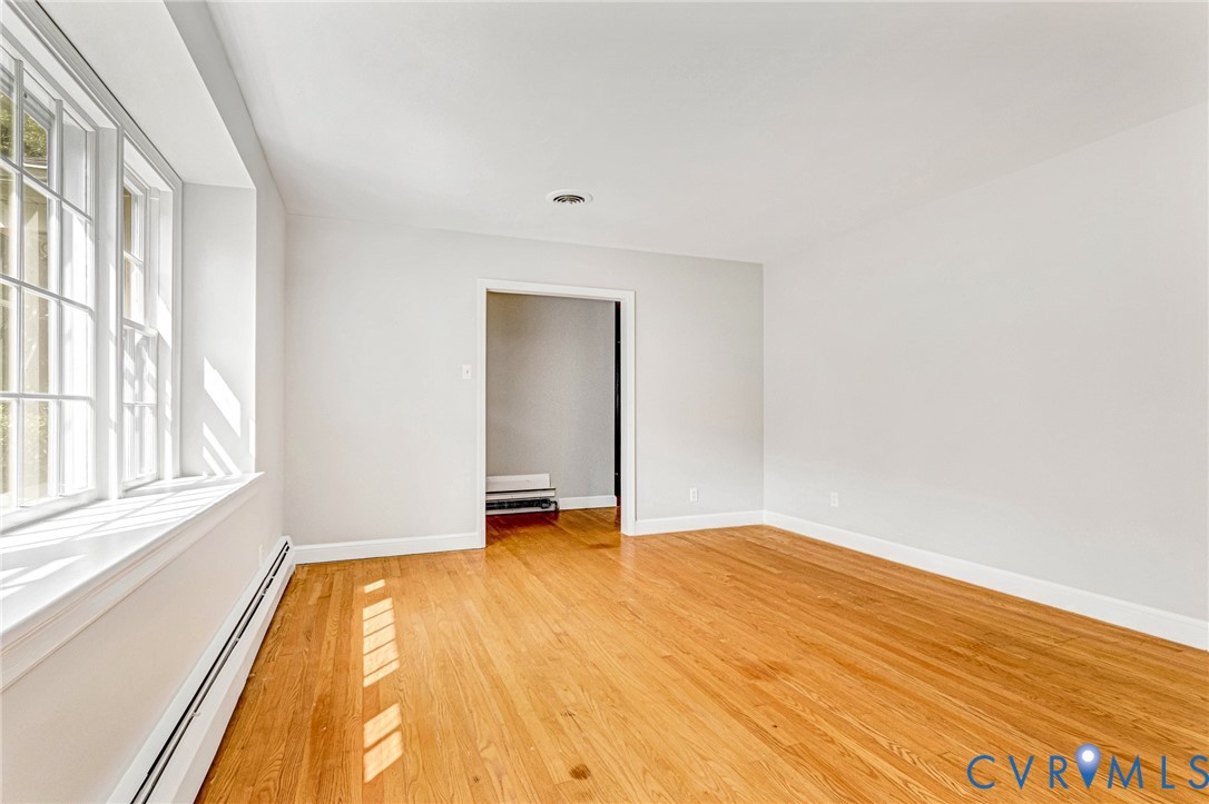 Wood-finish flooring, white painted walls, white trim, and a window with multiple panes Wood-finish flooring, white painted walls, white trim, and a window with multiple panes