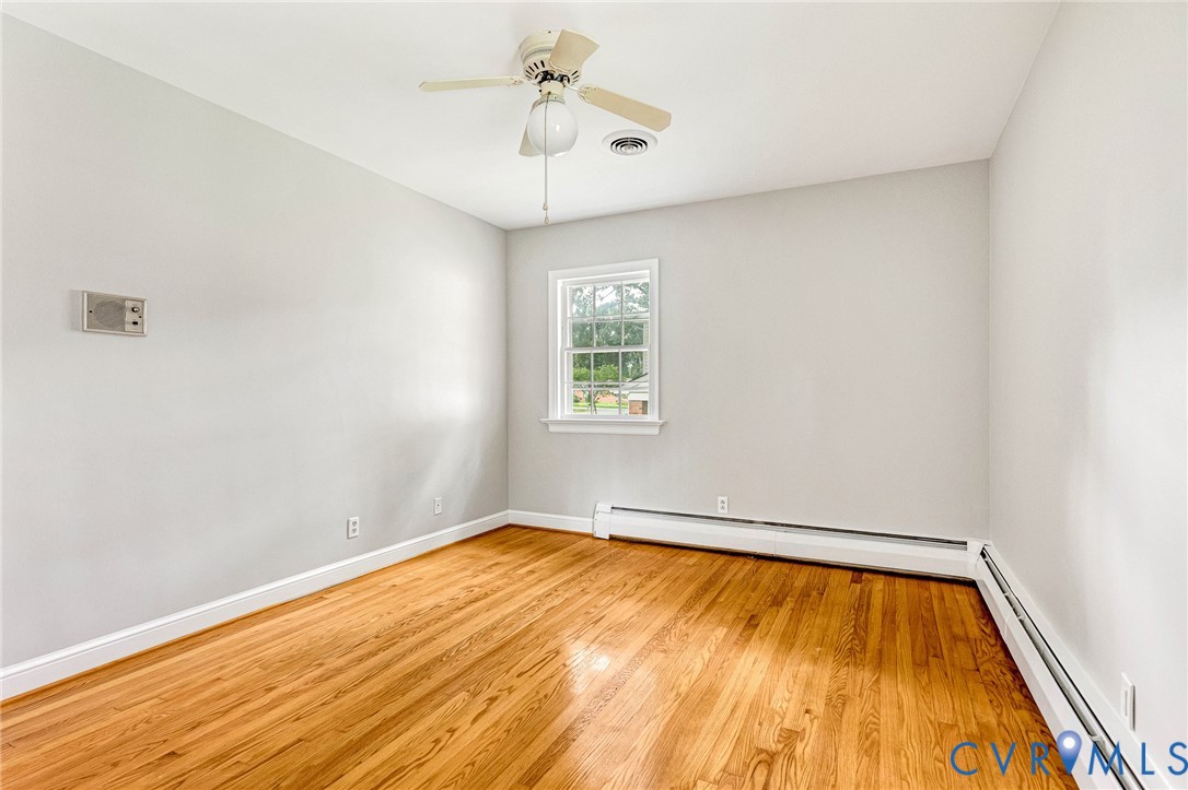 Hardwood flooring, central ceiling fan, and white trim molding