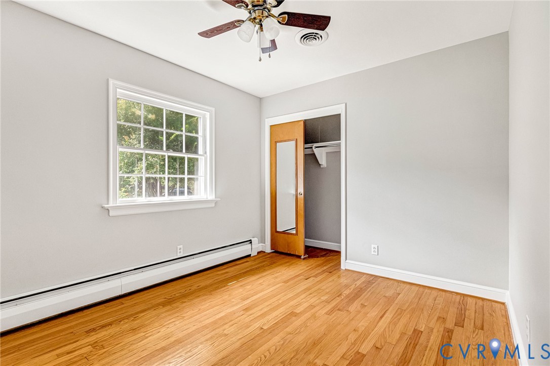 Hardwood flooring, white trim, ceiling fan, and a built-in closet