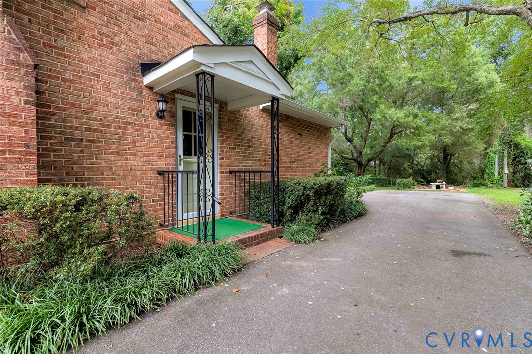Brick exterior featuring a covered entry with decorative wrought iron supports and handrails