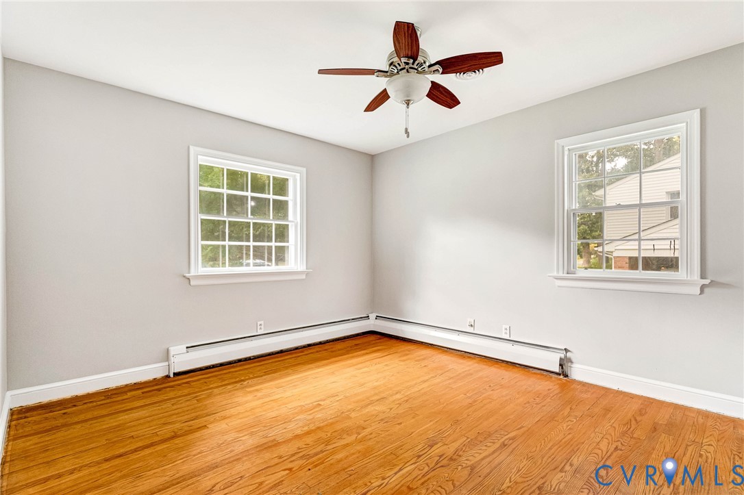 Hardwood flooring, painted walls, two multi-pane windows, and a ceiling fan with light fixture