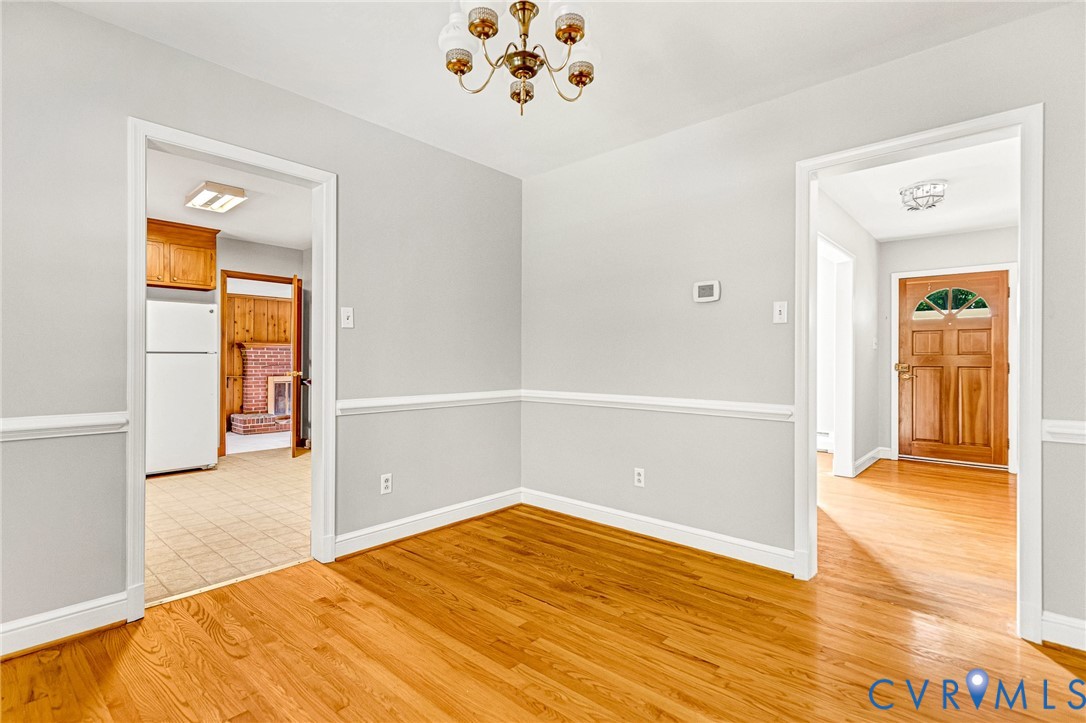 Hardwood flooring, painted walls with chair rail trim, and a brass chandelier