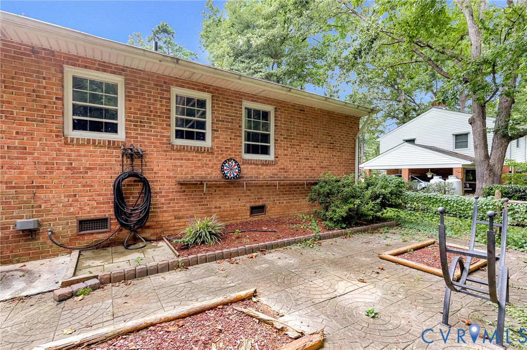 Brick exterior with multiple windows, concrete patio, and landscaping