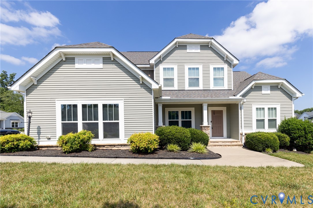Two-story exterior with horizontal siding, multiple gables, a covered porch, and mature foundation plantings Two-story exterior with horizontal siding, multiple gables, a covered porch, and mature foundation plantings