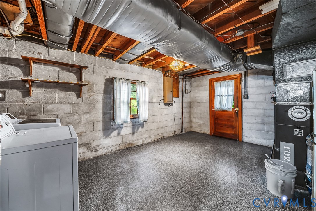 Concrete block walls, exposed wood ceiling joists, grey utility flooring, wood door, and a small window