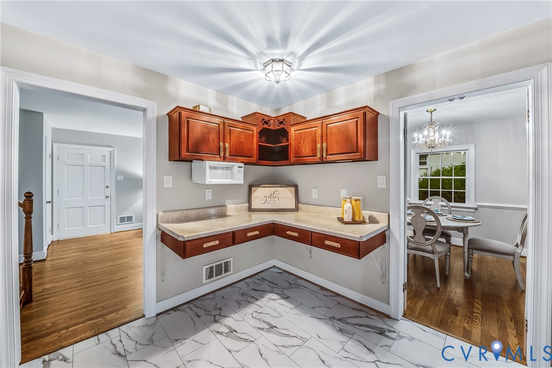 Built-in cabinetry with wood-finish doors, solid surface countertop, and marble-look tile flooring