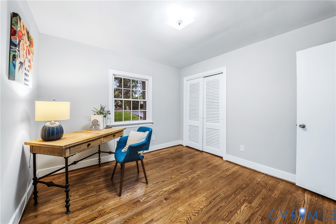 Hardwood flooring, painted walls, a window with exterior visibility, a closet with louvered bifold doors, and a flush mount ceiling light