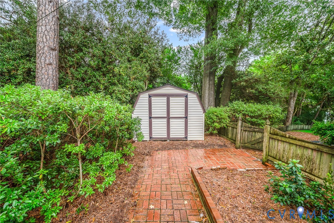 Outbuilding with double doors, brick paver pathway, and wood privacy fencing