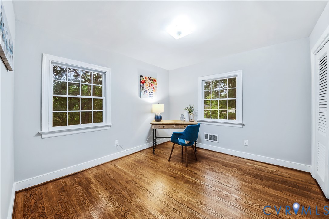 Hardwood flooring, painted walls, two multi-pane windows with white trim, and a built-in closet with louvered bifold doors