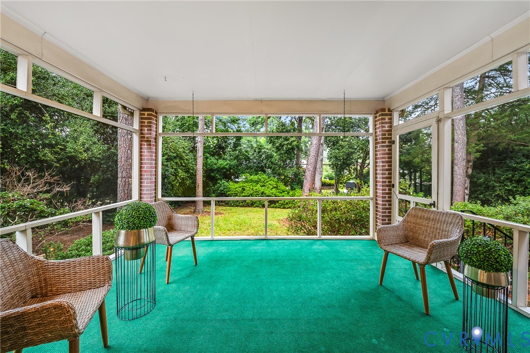 Screened porch with brick accents, bright green flooring, and white railing