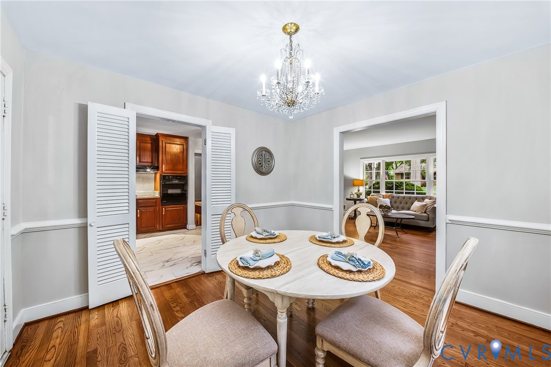 Hardwood flooring, crystal chandelier, decorative wall trim, louvered bi-fold doors, and recessed wall opening