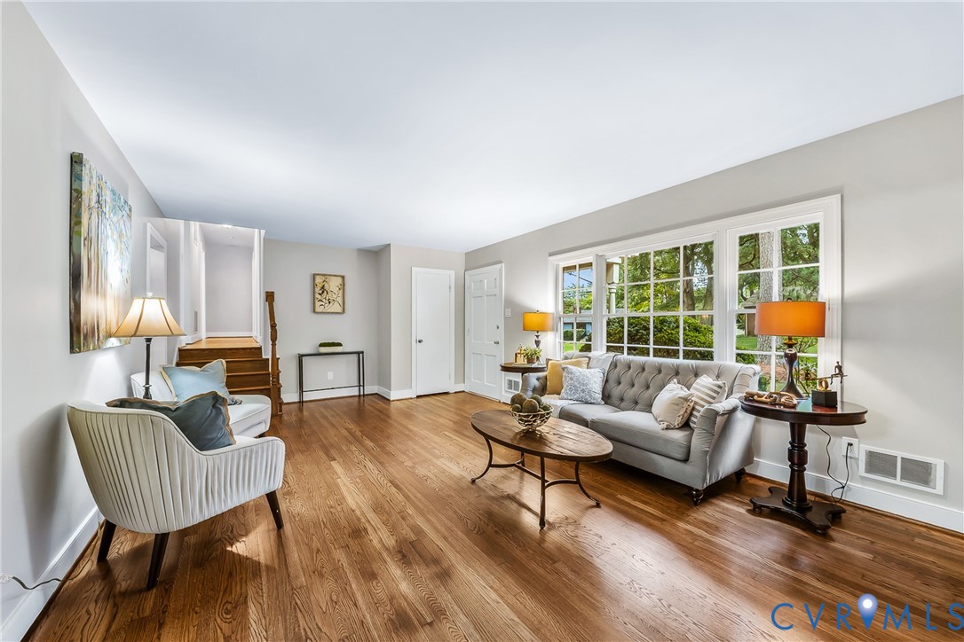 Hardwood flooring, white trim, multiple windows, and a staircase with wood railing Hardwood flooring, white trim, multiple windows, and a staircase with wood railing