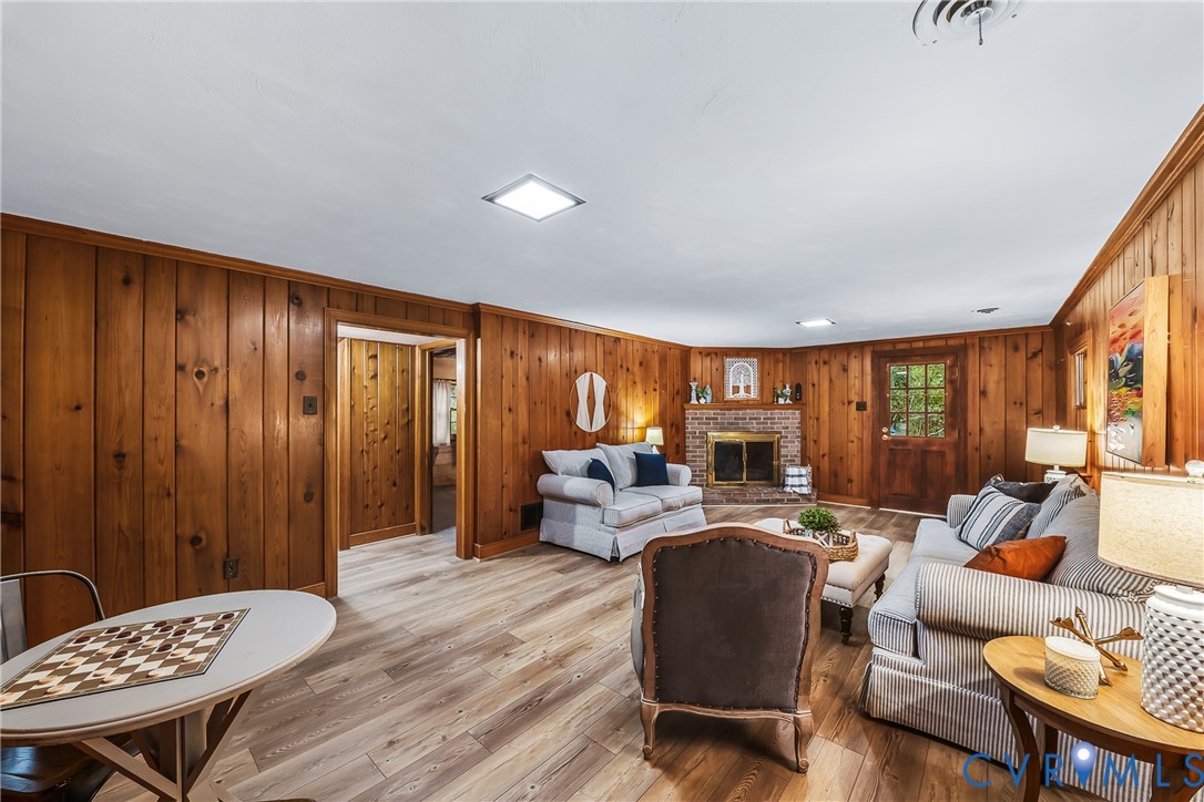 Wood paneling, wood-finish flooring, brick fireplace with metal insert, recessed lighting, and a wood door with glass panes