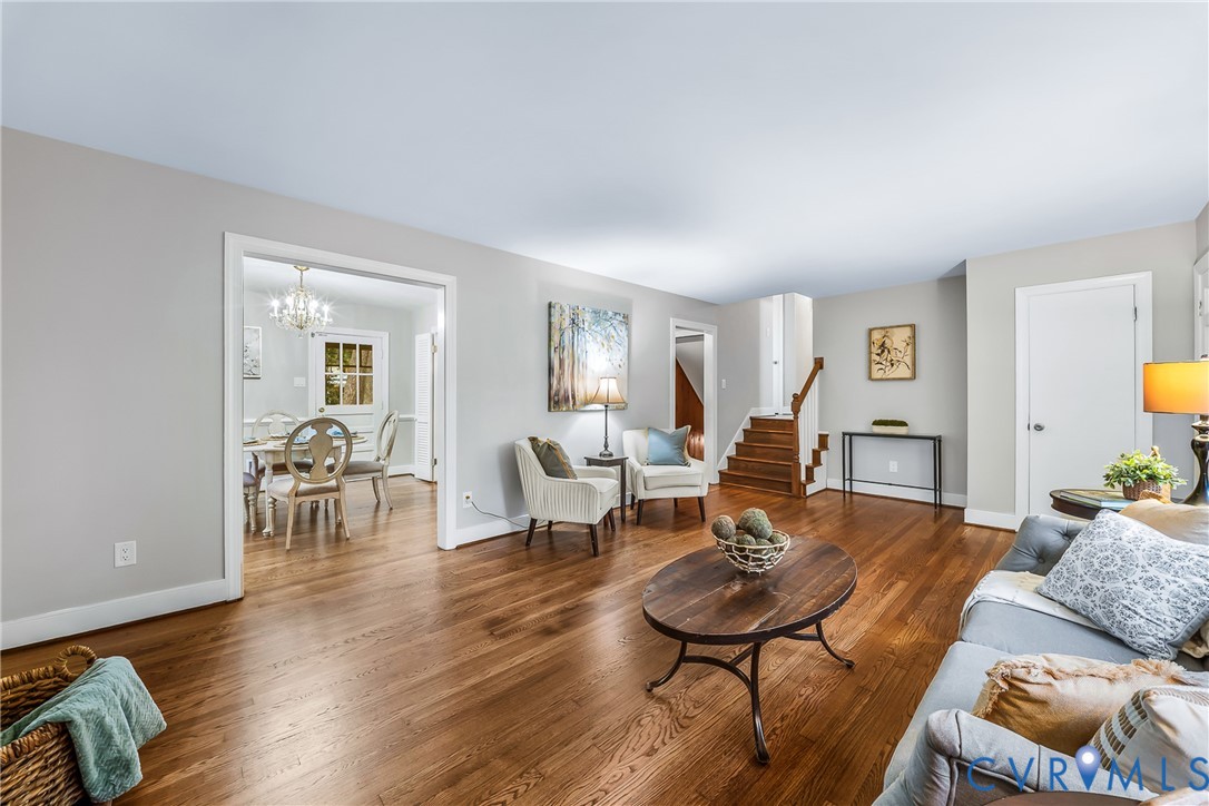 Hardwood flooring, painted walls, open archway, and wood staircase with white risers Hardwood flooring, painted walls, open archway, and wood staircase with white risers