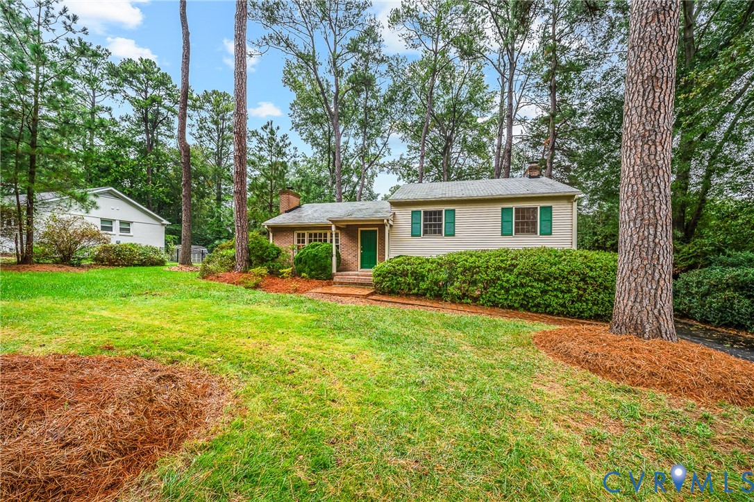 Brick and siding exterior with green shutters, surrounded by mature trees, and a spacious lawn with established landscaping Brick and siding exterior with green shutters, surrounded by mature trees, and a spacious lawn with established landscaping