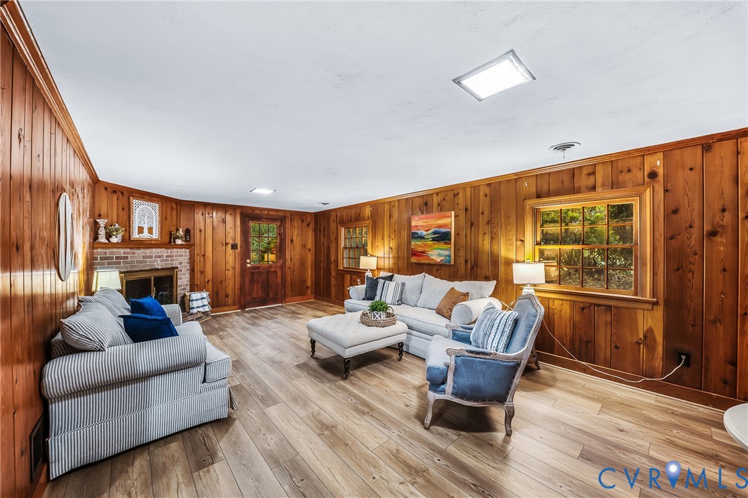 Wood-finish flooring, wood paneling, exposed brick fireplace, and built-in lighting fixtures