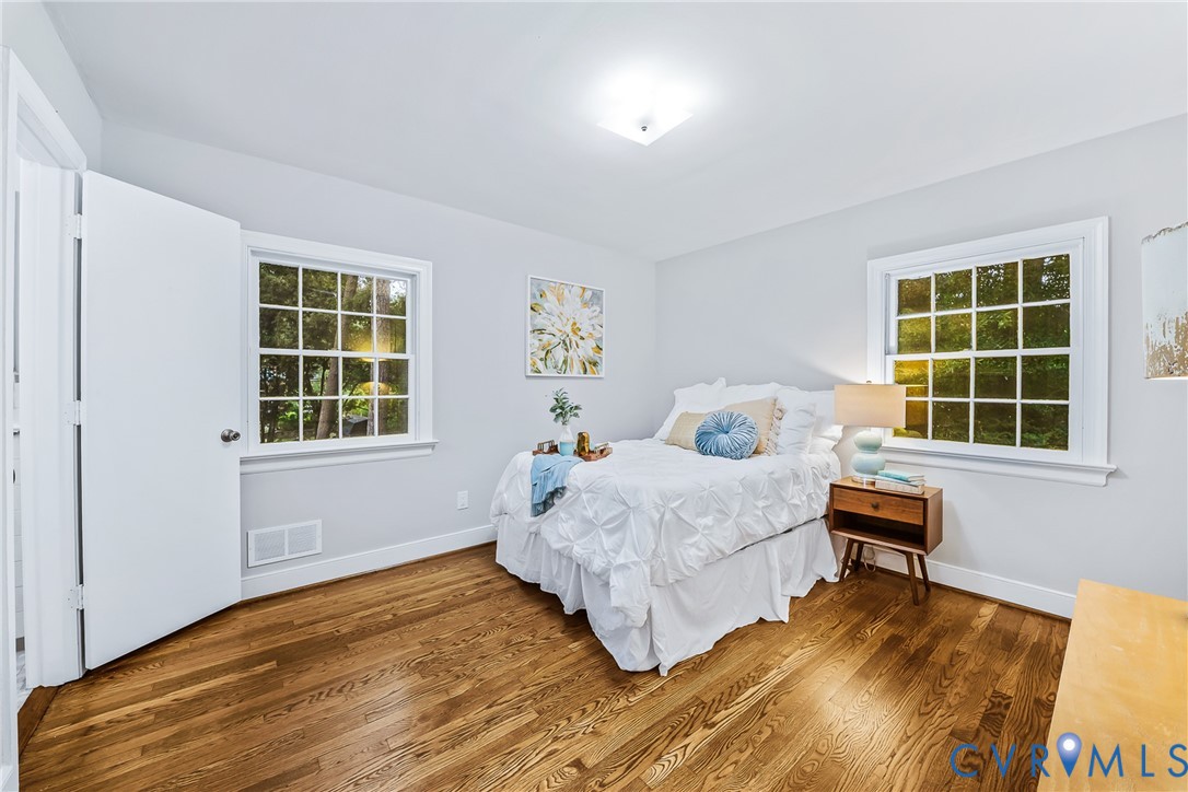 Hardwood flooring, two large windows, white trim, light wall color, ceiling-mounted light fixture