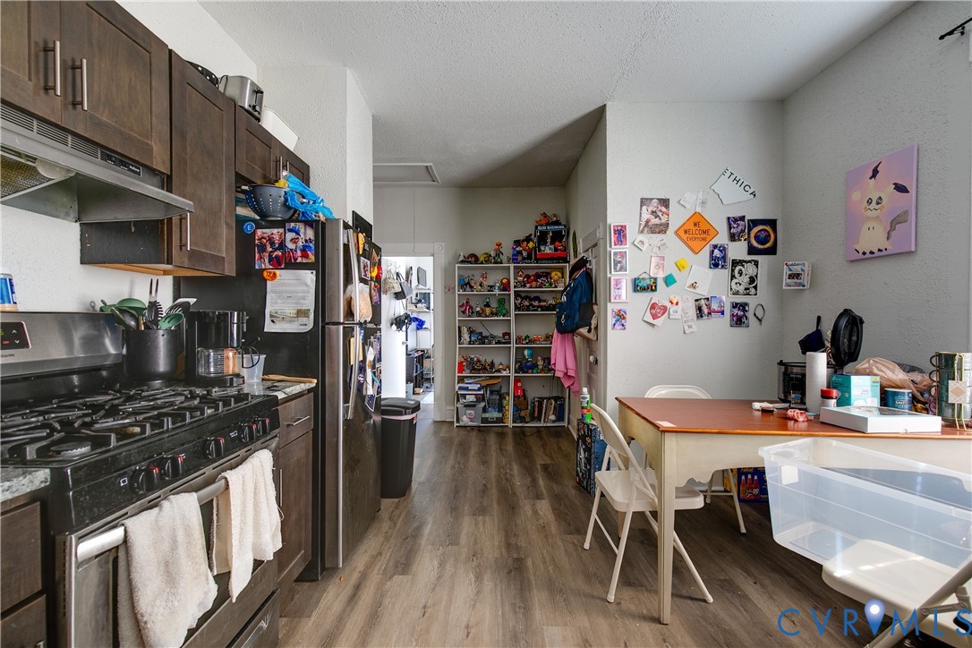Kitchen featuring wood-finish cabinetry, stainless steel range with hood, and stainless steel refrigerator