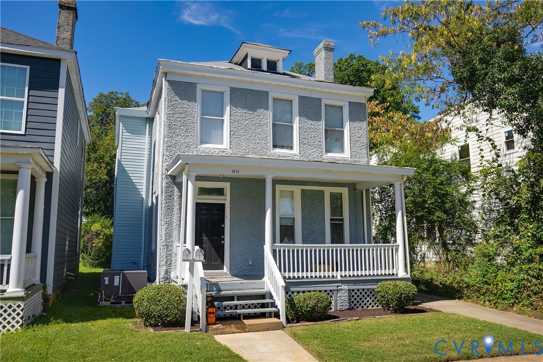 Two-story residence featuring a covered front porch, stucco exterior finish, and a dormer window