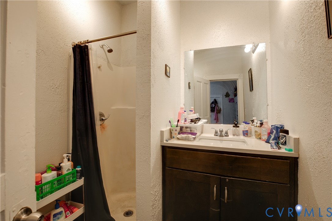 Vanity with an integrated sink, a dark wood-finish cabinet, and a wall-mounted mirror with overhead lighting