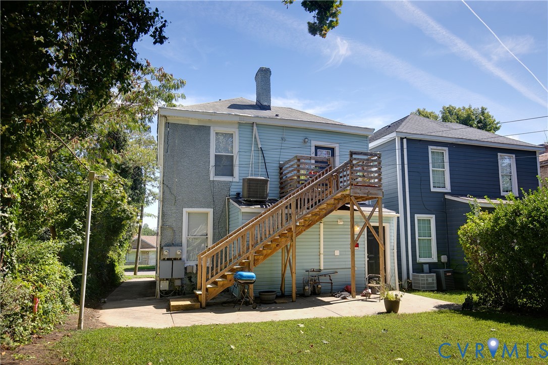 Rear concrete patio with wooden deck and staircase access