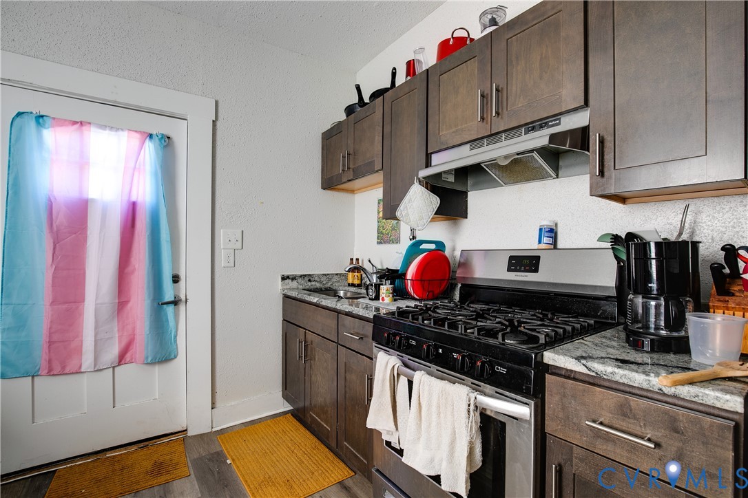 Modern kitchen featuring wood-finish cabinetry, stone-finish countertops, and stainless steel appliances
