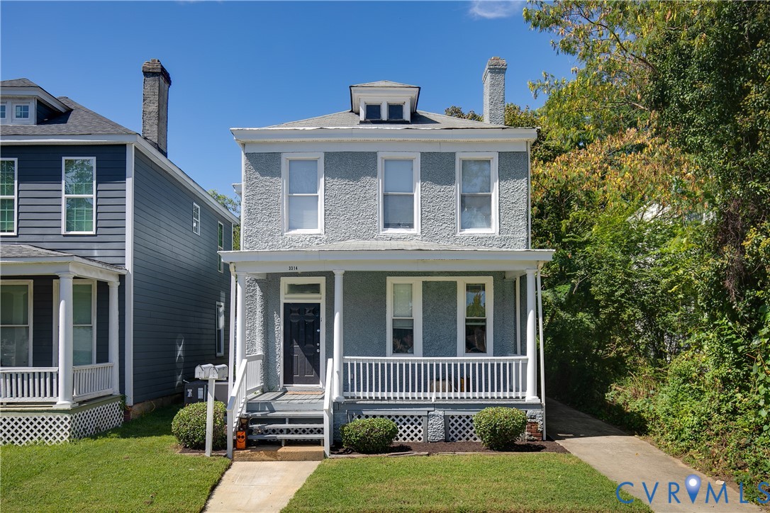 Stucco exterior with a covered front porch, white railing, and a gabled dormer