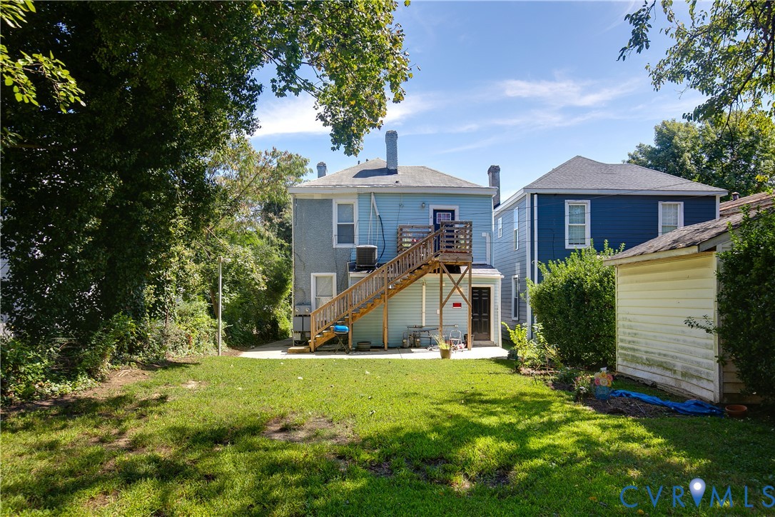 Expansive green space featuring a concrete patio, wooden deck, and a detached shed