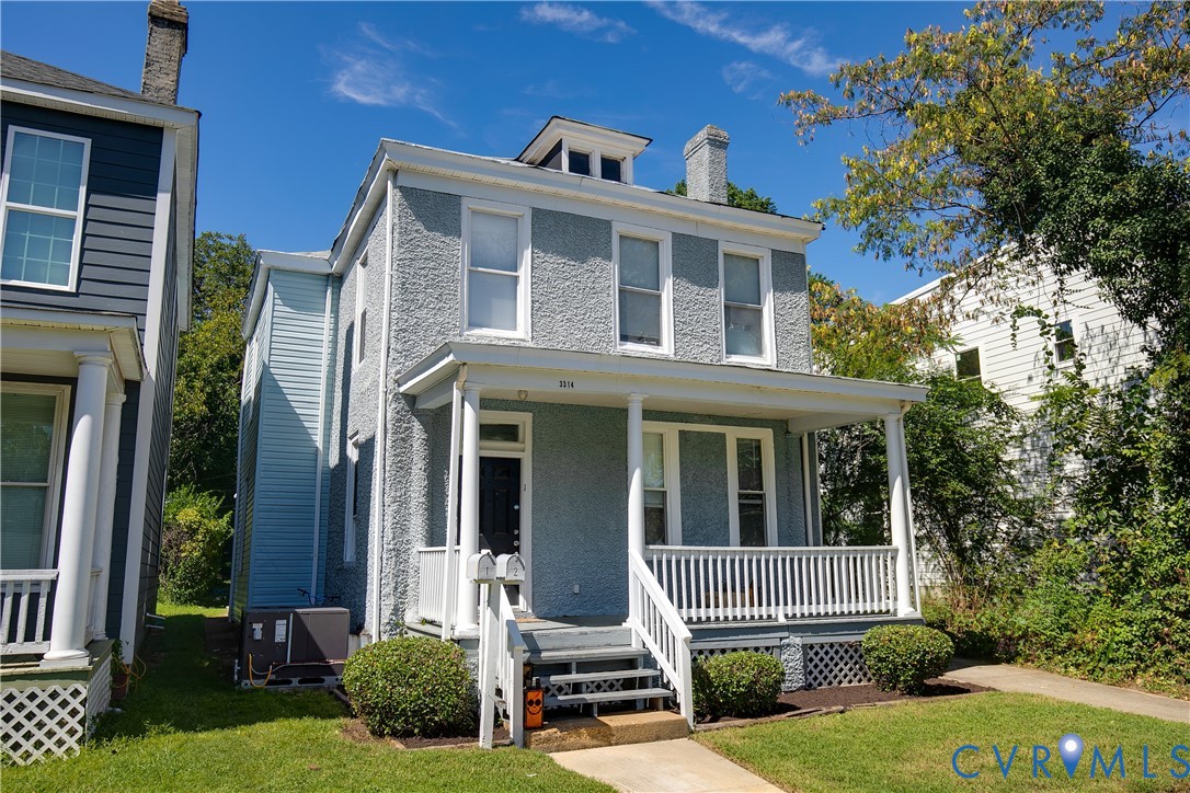 Classic Colonial-style residence featuring a light brick exterior with substantial front porch and white railing detail