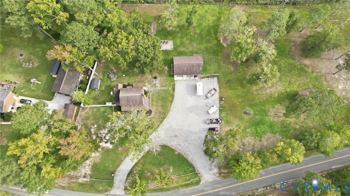 Multiple structures on a spacious, tree-lined property with a gravel driveway