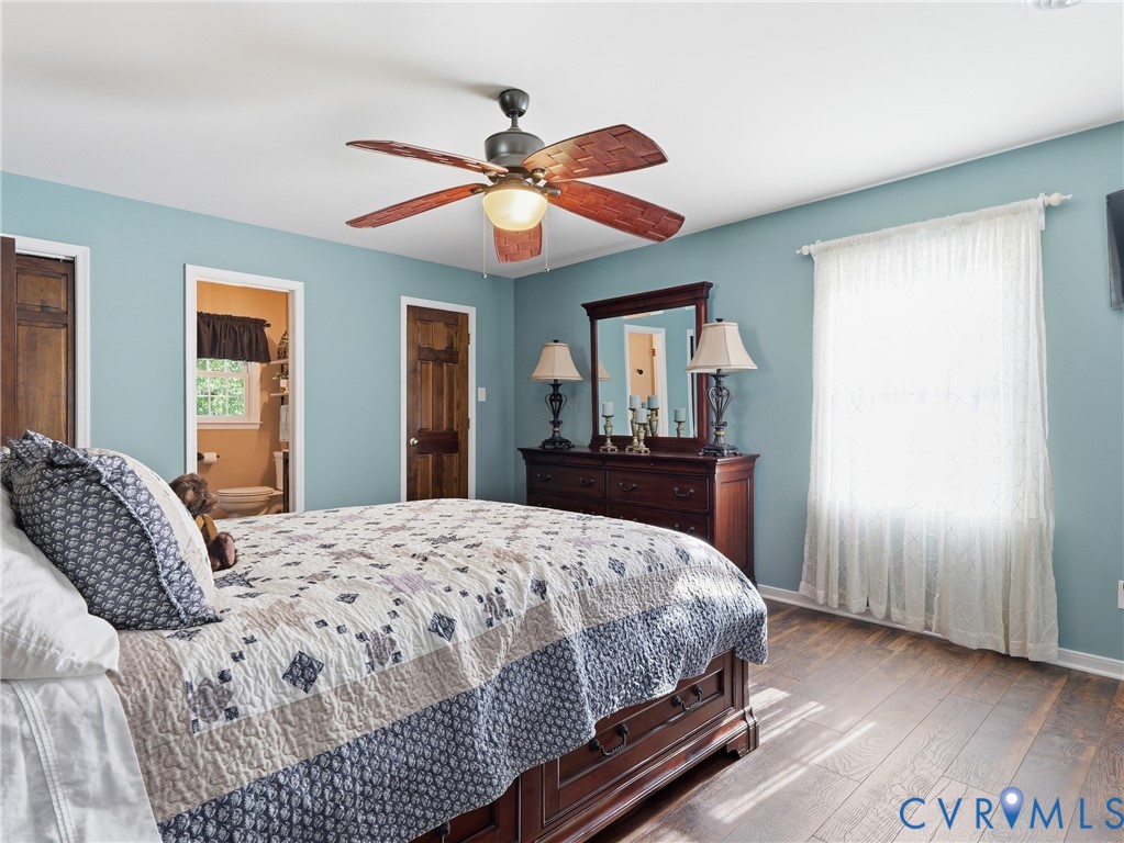 Room interior featuring wood-finish flooring, a ceiling fan with integrated lighting, and natural wood-finish interior doors