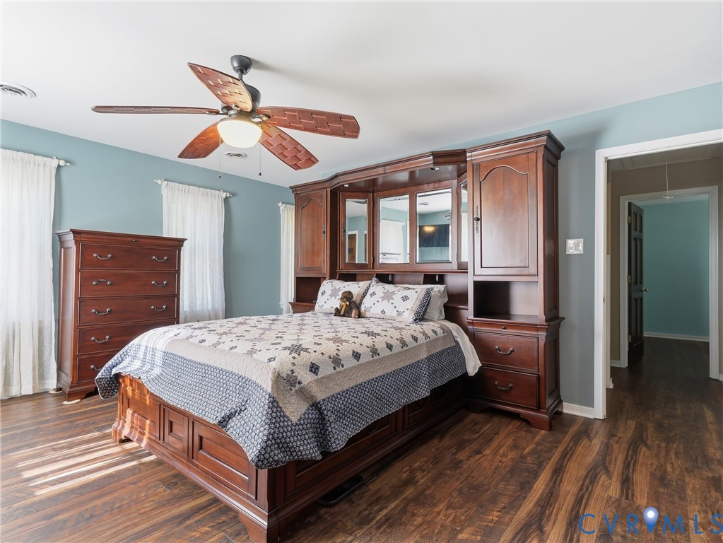 Wood-finish flooring, built-in wooden cabinetry featuring mirrored panels, and a multi-blade ceiling fan with integrated lighting