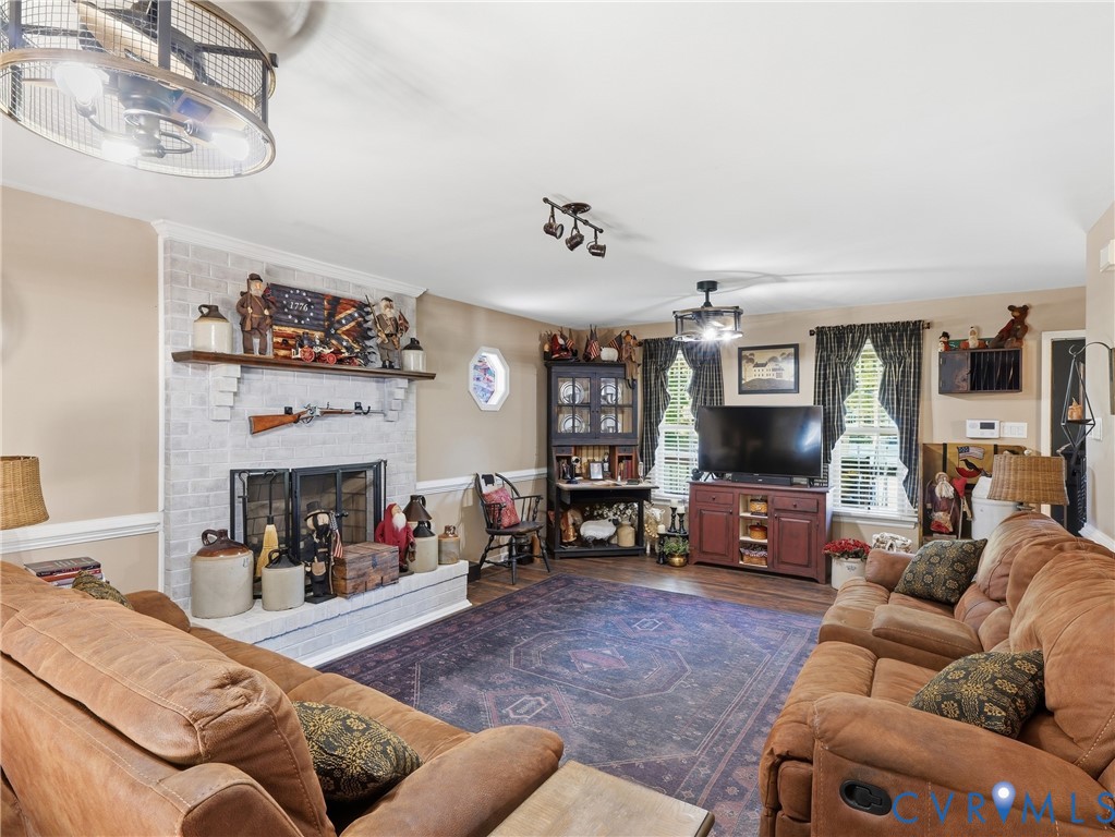 Painted brick fireplace featuring a wood mantel, octagonal window, two metal-frame drum chandeliers, and wood-finish flooring